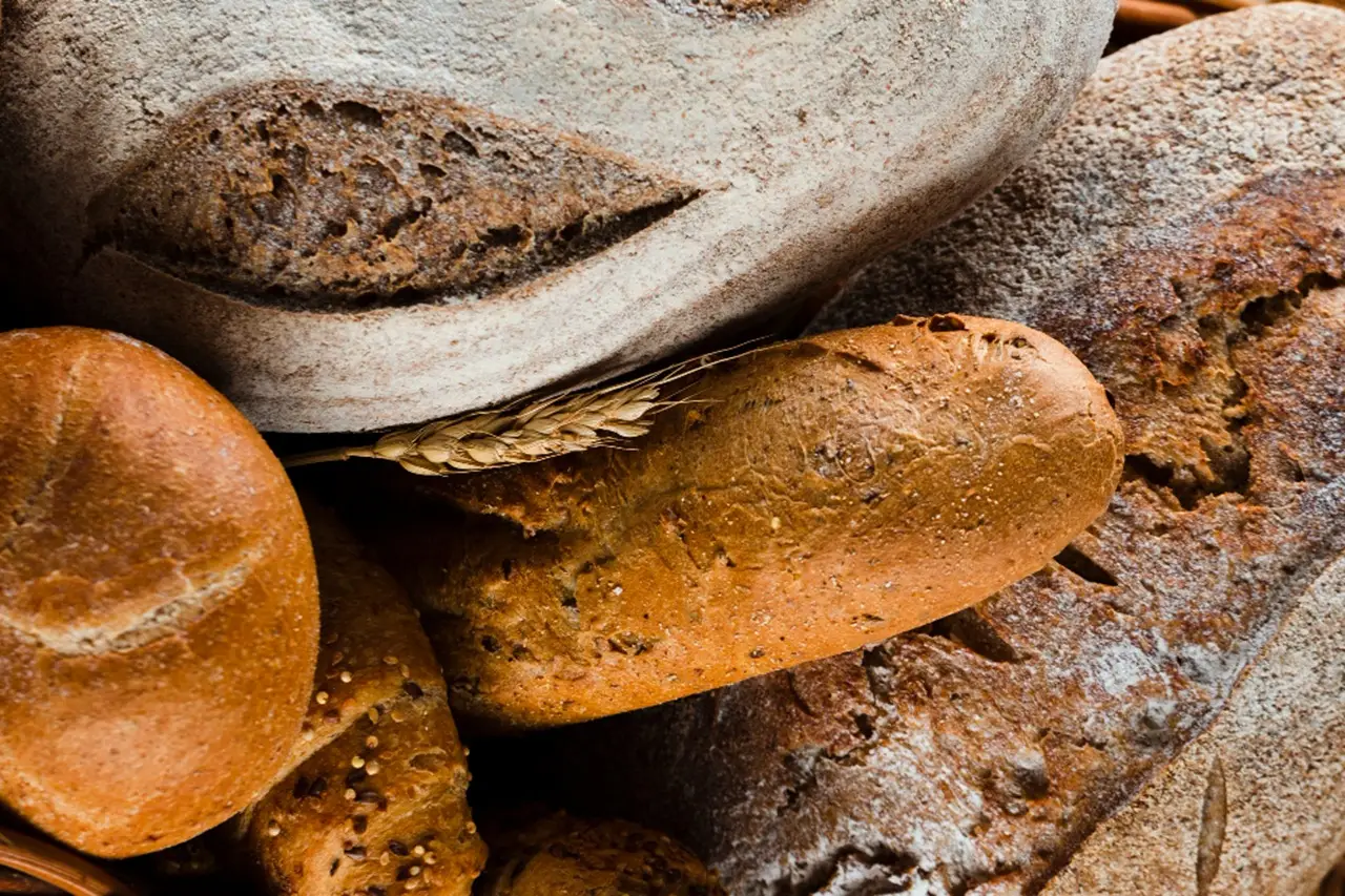 Il pane che fa bene: migliora la digestione e tiene sotto controllo la glicemia SP - Pane integrale su tagliere e mano che lo taglia